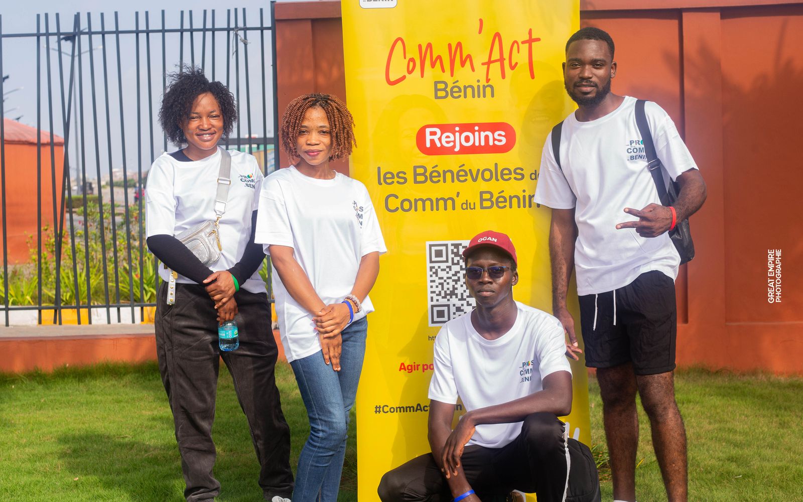Quatre bénévoles COMM’ACT Bénin posent devant le kakémono « Rejoins les bénévoles de la Comm’ du Bénin »